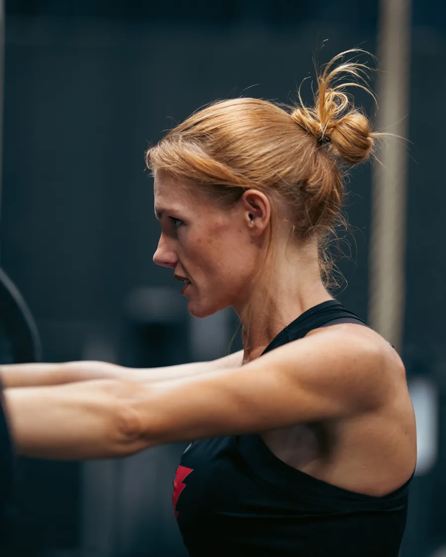 Athlete front-racking a sandbag in a dark gym
