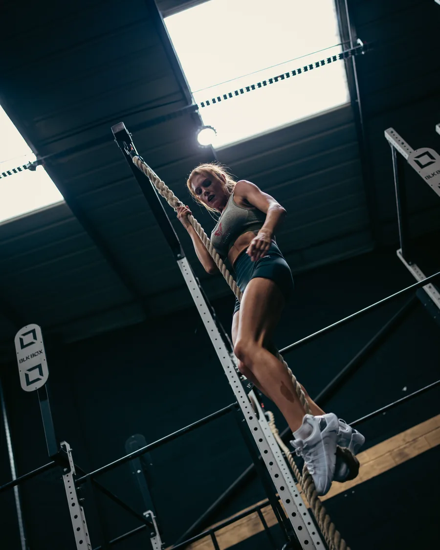 Athlete driving battle ropes in a dark gym